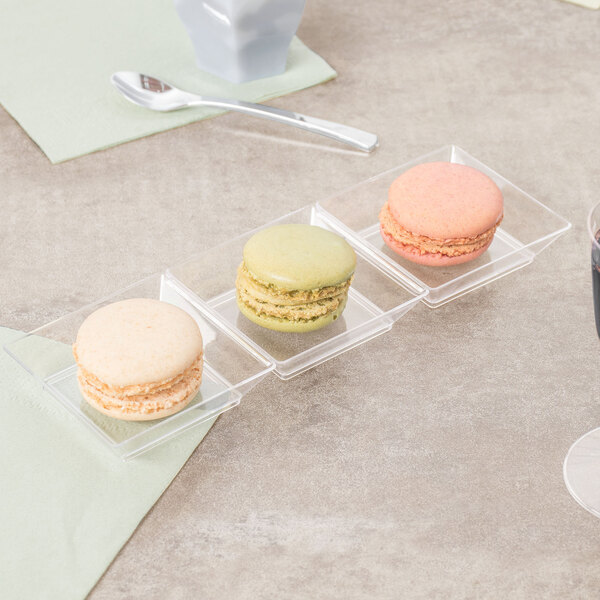 A Fineline clear plastic sectional tray with macarons on a table.