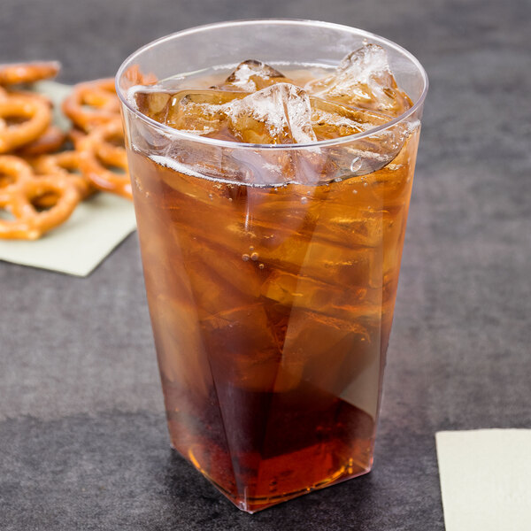 A clear square bottom Fineline tumbler filled with ice tea on a table with pretzels.