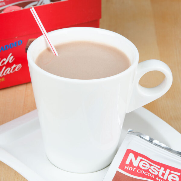 A cup of hot chocolate with a straw and a red and white packet of Nestle No Sugar Added Hot Cocoa Mix.