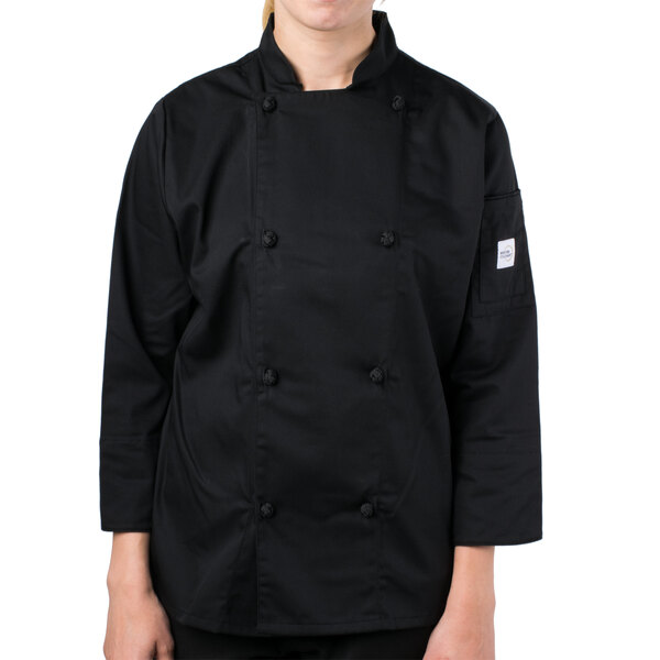 A young woman wearing a Mercer Culinary Genesis black long sleeve chef jacket.