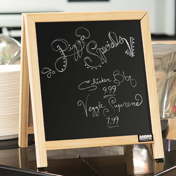 An Aarco tabletop A-frame chalkboard with writing on it.