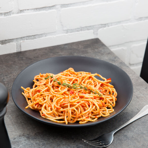 A 10 Strawberry Street black stoneware plate with spaghetti and a fork.