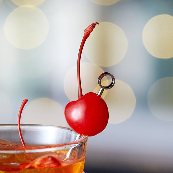 A close-up of a Regal orange maraschino cherry with a stem on top of a drink.