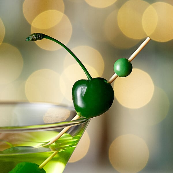 A green Regal Maraschino cherry on a stem in a martini glass.
