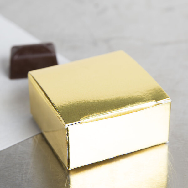 A gold foil square candy box with a square top.