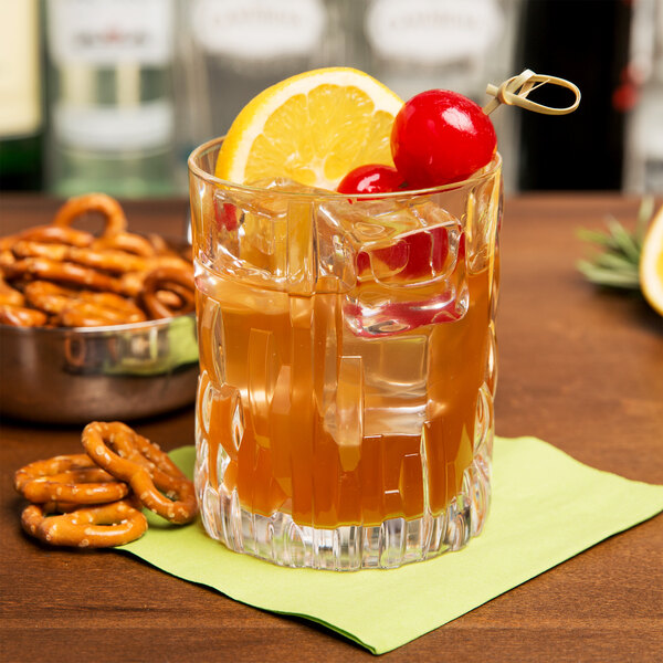 A Nachtmann Shu Fa rocks glass filled with ice tea, a lemon slice, and a cherry on a table.