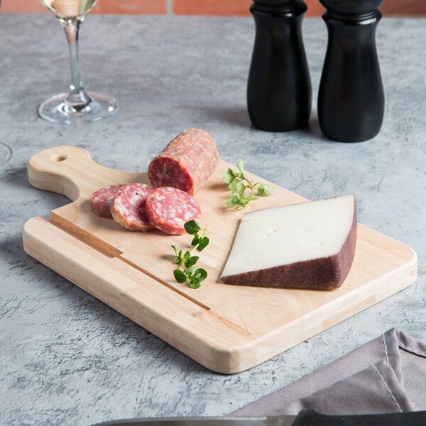 A Choice wooden serving and cutting board with cheese, sausage, and wine.