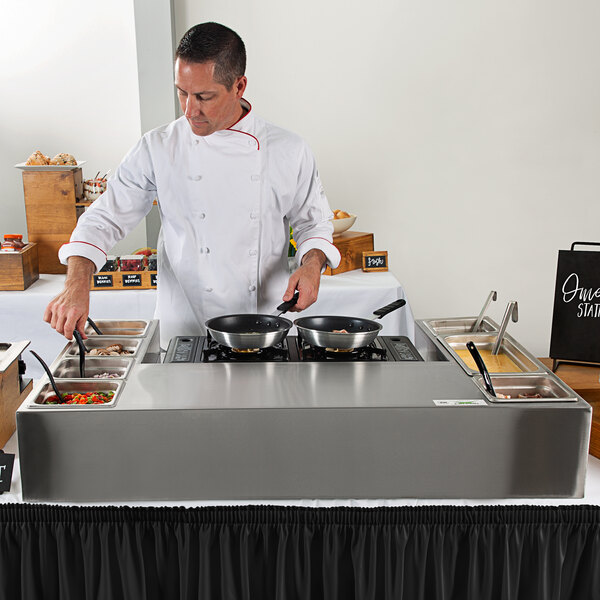 A chef using a Choice Deluxe Butane Made-to-Order Omelet / Pasta Station Kit to cook food on a table in a kitchen.