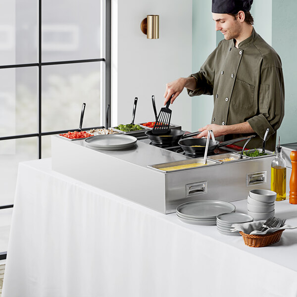 A man using an Avantco induction omelet and pasta station to cook food.