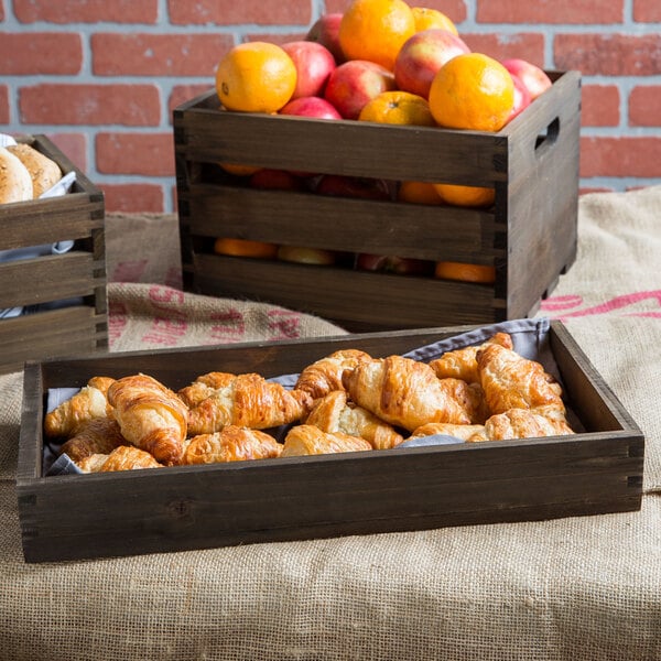 An American Metalcraft vintage wood crate filled with oranges and croissants on a table in a bakery.