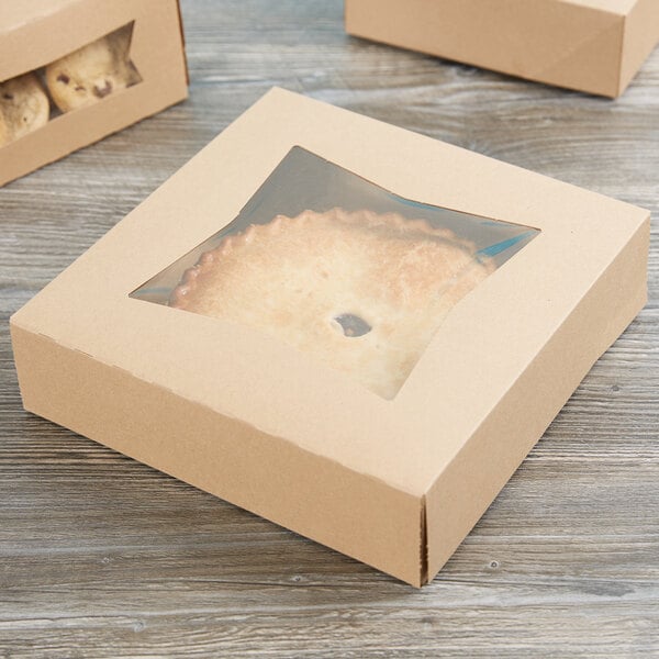 A Kraft bakery box with a window filled with cookies on a table.