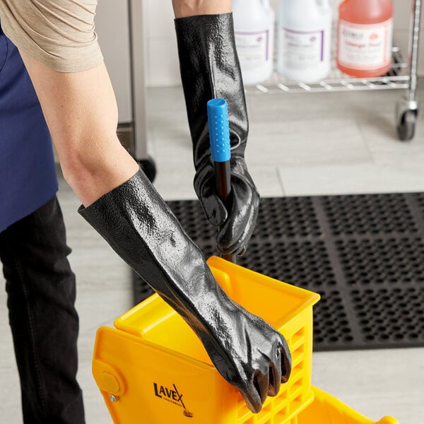 A person wearing Cordova black gloves cleaning a yellow container.
