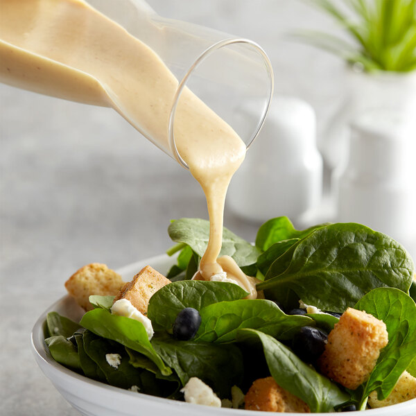 A salad with Hidden Valley Golden Honey Mustard Dressing being poured on it.