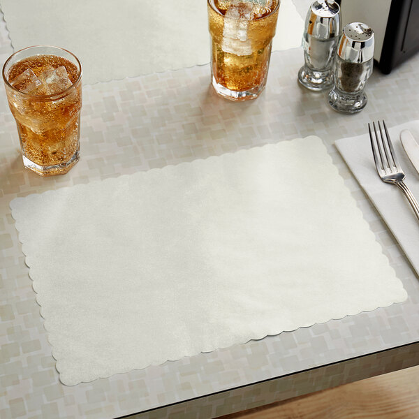 A gray scalloped paper placemat on a table with glasses of ice tea.