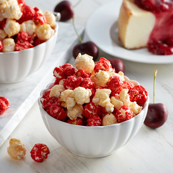 A bowl of Grandma Jack's Gourmet Cherry Cheesecake Popcorn with a slice of cheesecake.