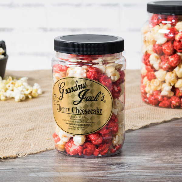 A jar of Grandma Jack's Gourmet Cherry Cheesecake Popcorn on a table with red and white sprinkles.