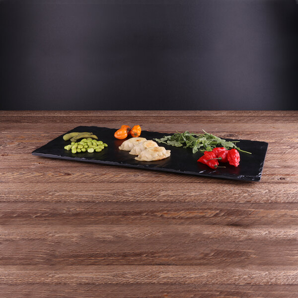 An Elite Global Solutions black faux slate melamine serving board with food on it.