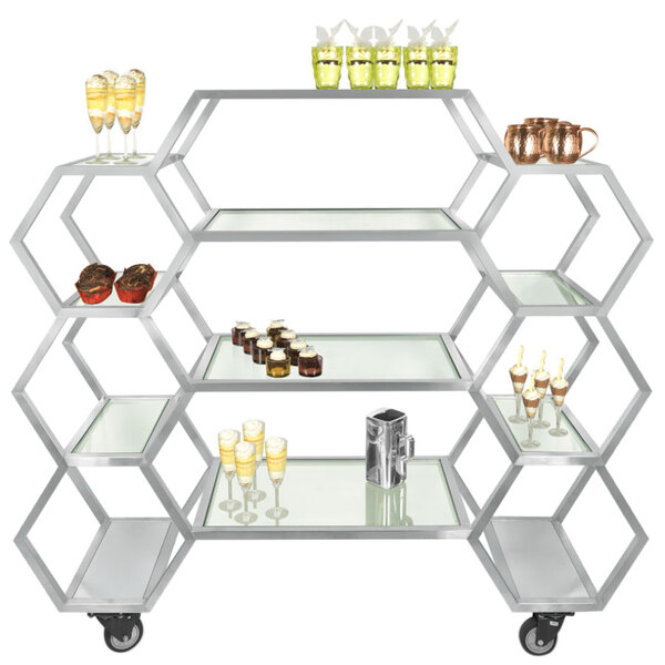 An Eastern Tabletop stainless steel rolling buffet with clear glass shelves holding drinks.