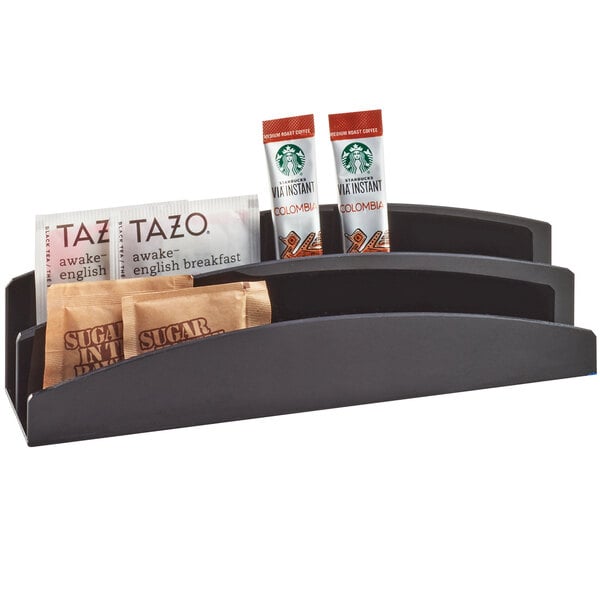 A black Cal-Mil coffee condiment packet organizer on a counter filled with condiment packets.