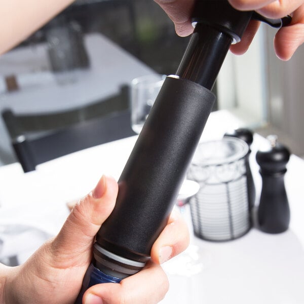 A hand using the Vacu Vin wine saver to pump air out of a bottle of wine.