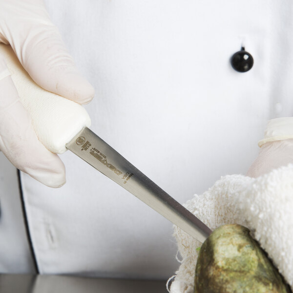 A gloved hand uses a Dexter Russell Boston style oyster knife to cut a rock.