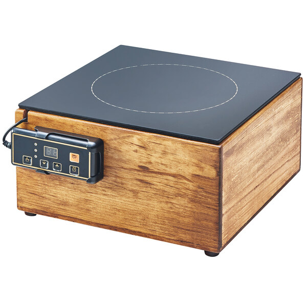 A wooden box with a black surface and a Cal-Mil Madera countertop induction cooker inside.