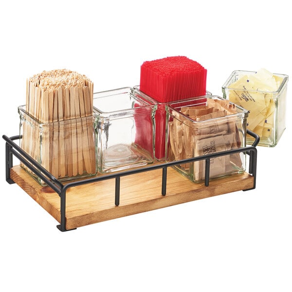 A wooden tray with 6 square glass jars on a counter.