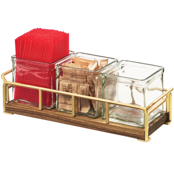 A Cal-Mil jar organizer with brass frame holding brown sugar packets in a glass container.
