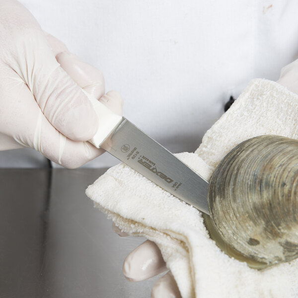 A person in white gloves using a Dexter Russell clam knife to open a clam.