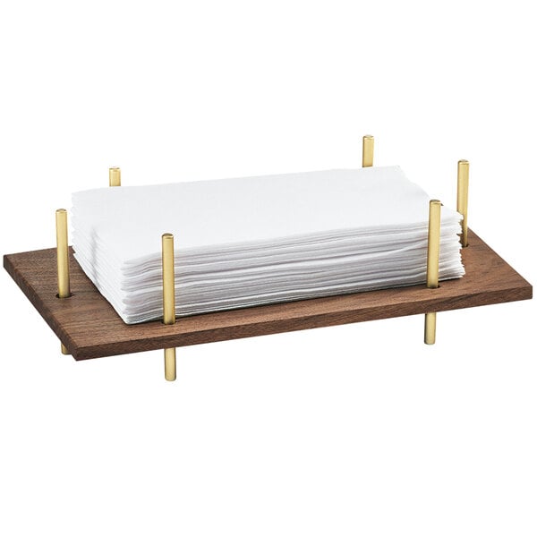 A wooden tray with a brass frame holding white napkins.