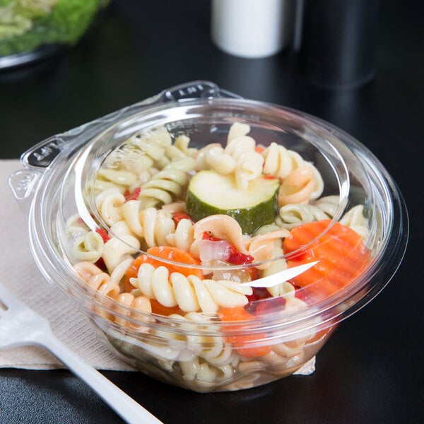 A Dart plastic bowl with pasta and vegetables in it with a plastic fork.
