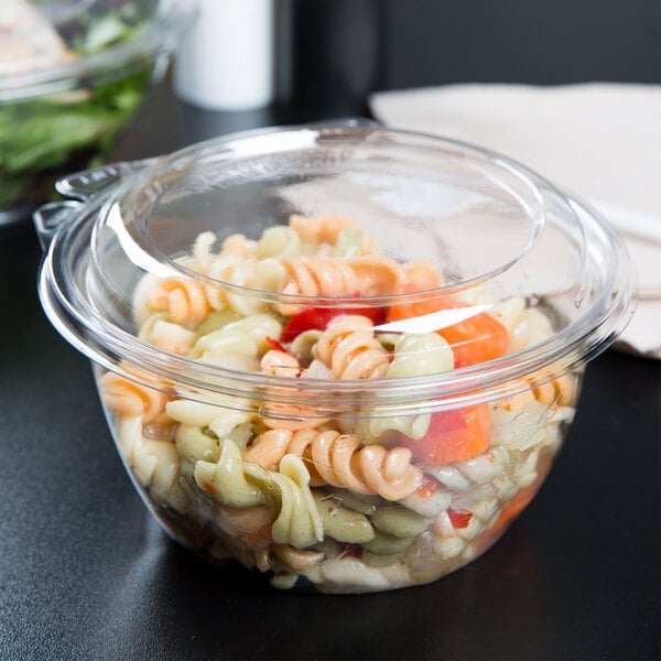 A clear plastic Dart deli bowl with pasta inside and a clear plastic lid.