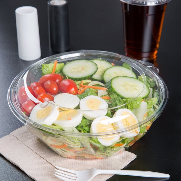 A salad in a Dart plastic bowl with a clear dome lid.