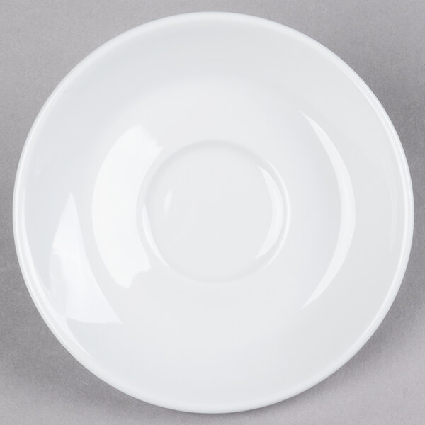 A close-up of a Tuxton porcelain white saucer with a small rim on a gray surface.