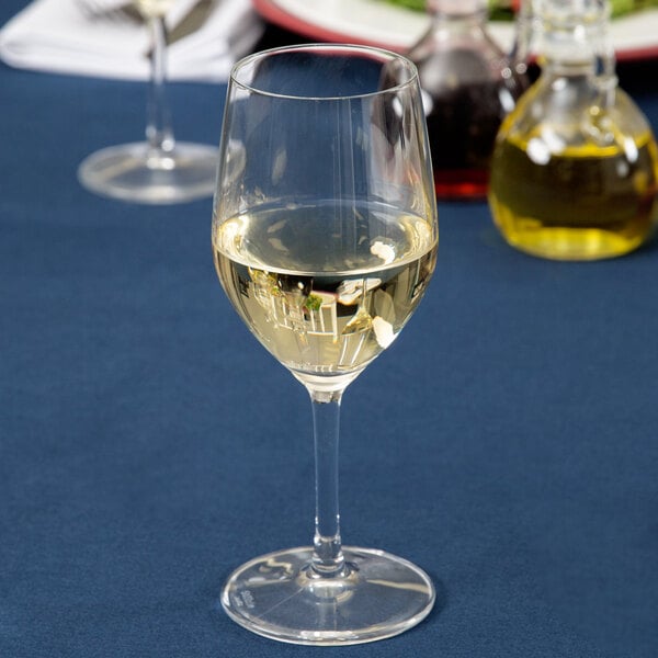 A close-up of a Stolzle white wine glass filled with white wine on a table.