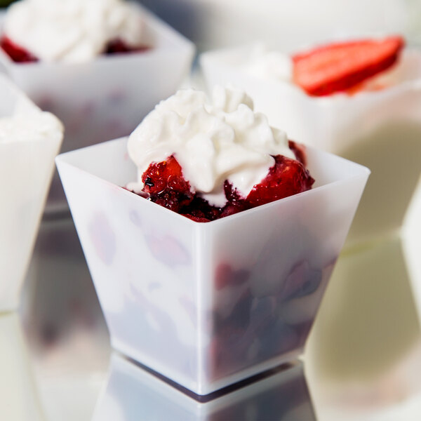 Fineline white plastic cube bowls filled with strawberries and whipped cream.