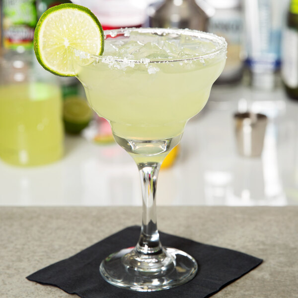 A Libbey margarita glass with a margarita and a lime wedge.