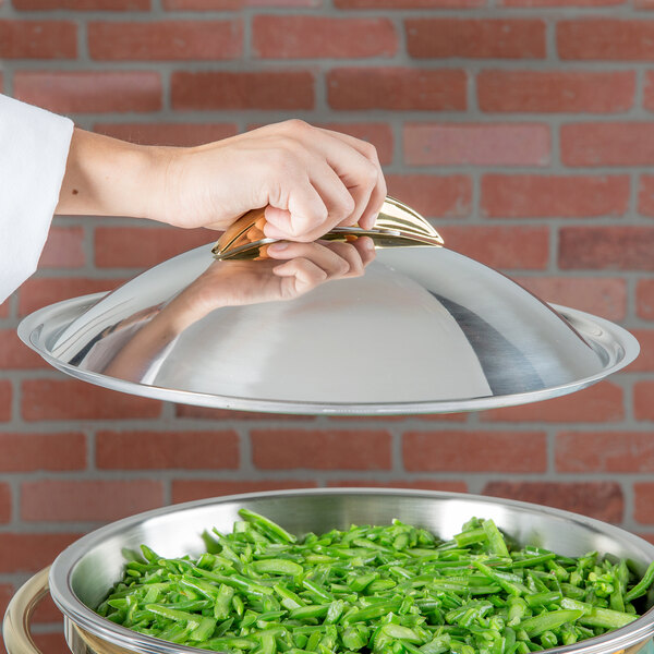 A person holding a Vollrath Panacea chafer cover over a bowl of green beans.