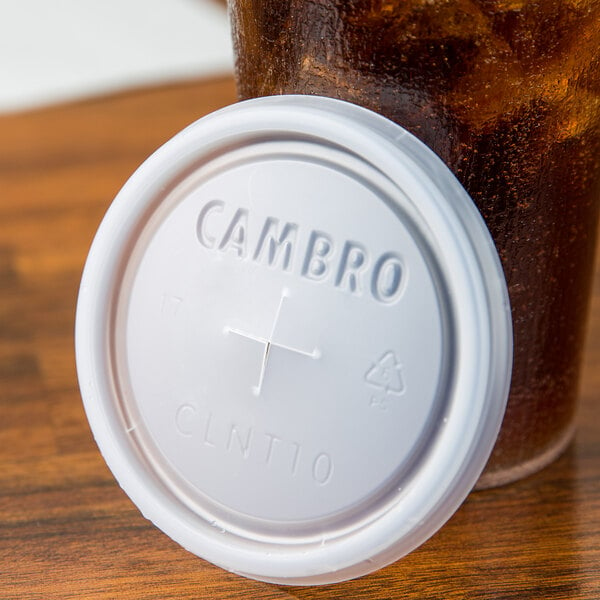 A white plastic Cambro lid with a straw slot on a plastic cup.