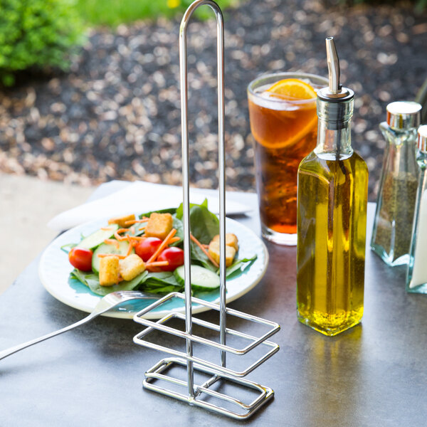 A Tablecraft chrome metal holder on a table with a bottle of olive oil.