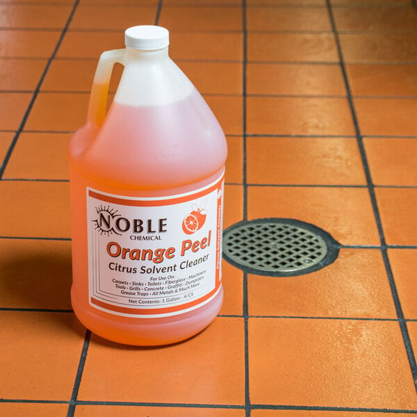 A jug of Noble Chemical Orange Peel citrus cleaner on a tile floor.
