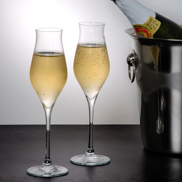 Two Stolzle flute glasses filled with champagne in a bucket.