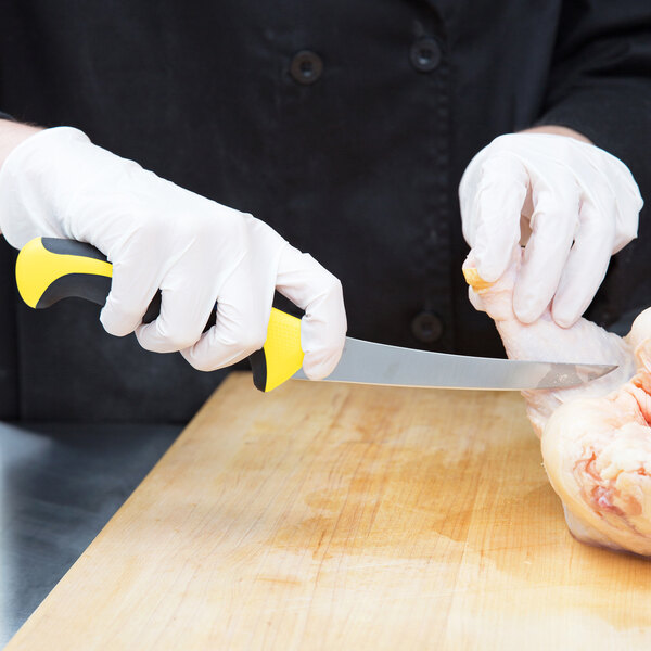 A person in white gloves using a Mercer yellow curved stiff boning knife to cut chicken.