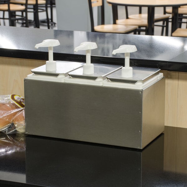A Carlisle stainless steel condiment dispenser rail with 3 standard pumps on a counter.