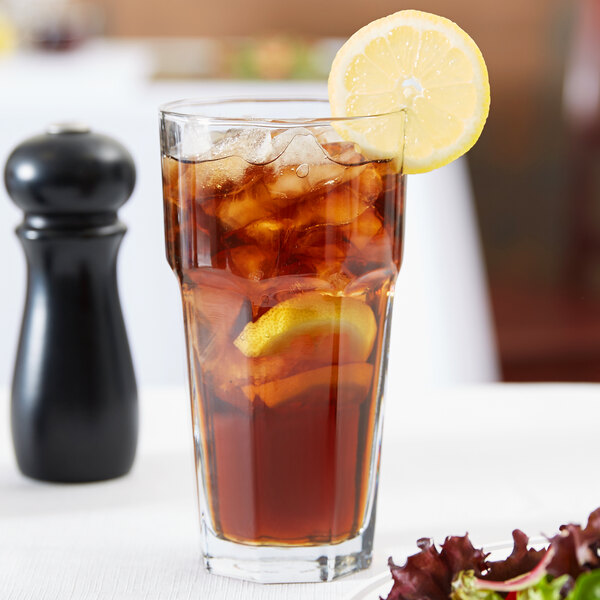 A glass of iced tea with lemon slices and ice.