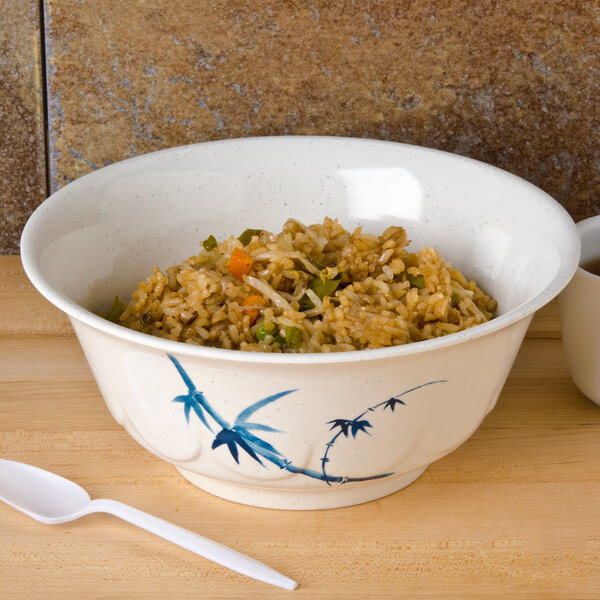 A blue melamine scalloped bowl filled with rice and vegetables with a white spoon.