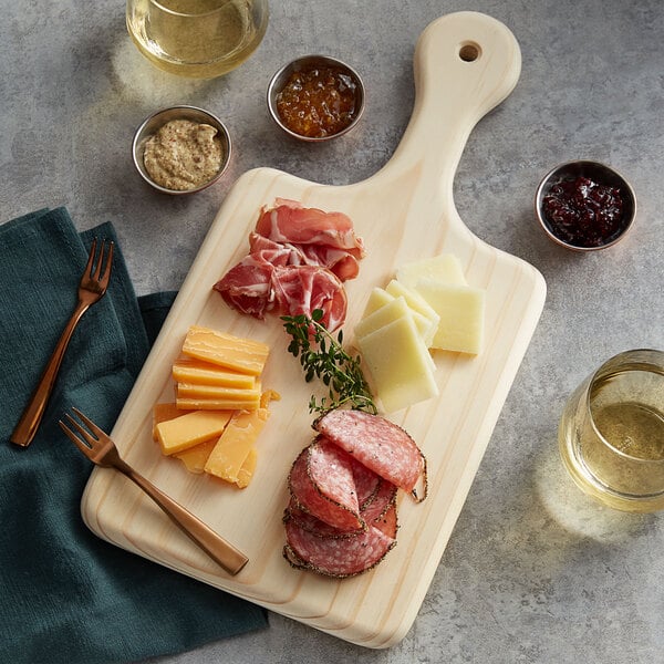 An American Metalcraft rubber wood charcuterie board with a stack of sliced salami, different types of meats and cheese, and a bowl of jam.