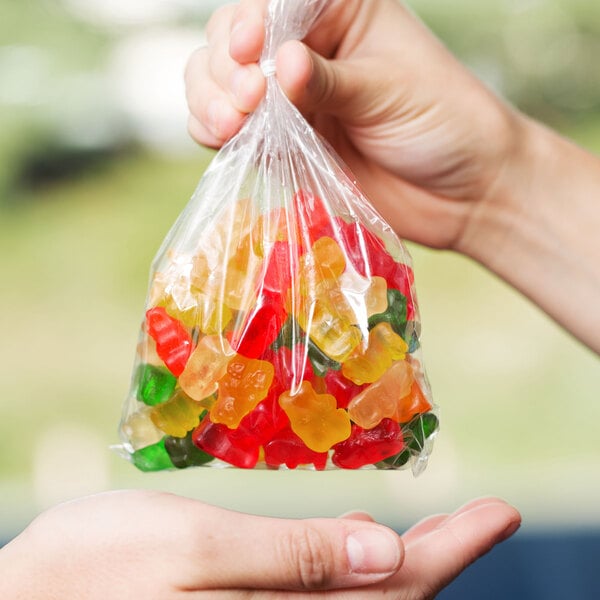 A hand holding a LK Packaging plastic food bag filled with gummy bears.