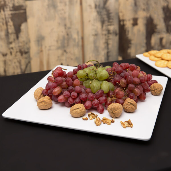 An American Metalcraft square melamine platter with grapes and nuts on a table.