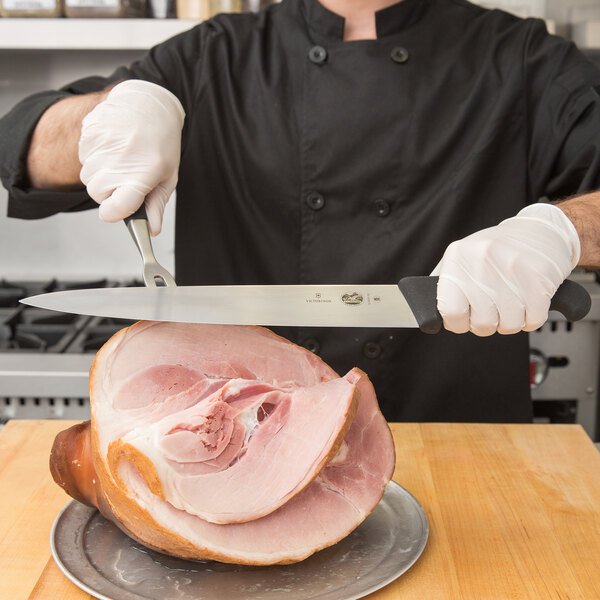 A person using a Victorinox Carving Knife to slice ham.